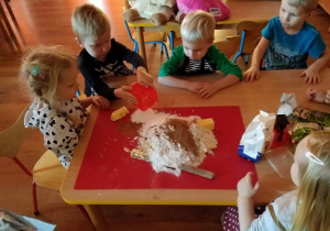 Dzieci dokładają na stolnicę składniki na pierniczki.